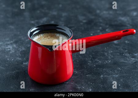 Heißer türkischer Kaffee in roter Kanne auf dunklem Hintergrund, Nahaufnahme Stockfoto