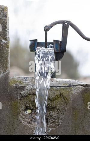 Eine alte Pumpe wurde verwendet, um Wasser aus dem Feld in der Türkei zu extrahieren. Retro-Brunnenpumpe, alte manuelle Wasserpumpe (Hebel). Gusseisenwasserpumpe im Vintage-Stil. 4K-Videoaufnahme. Stockfoto