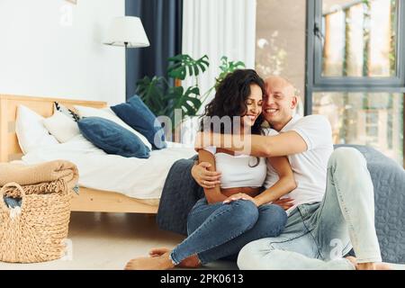 Sitzen und einander umarmen. Fröhliches Paar ist drinnen zusammen Stockfoto
