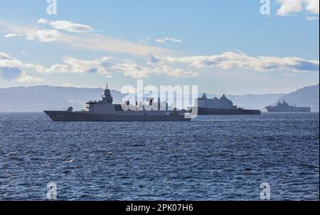 Die holländische Fregatte HNLMS De Ruyter begleitet amphipöse Angriffsschiffe in einem norwegischen Fjord während NATO-Übungen. Stockfoto