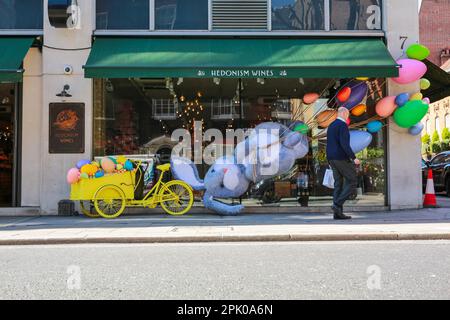 London, Großbritannien. 04. April 2023 Ein Mann geht vorbei an einem riesigen Osterhasen und Eiern vor Hedonism Wines in Mayfair - Osterdekorationen. © Waldemar Sikora Stockfoto