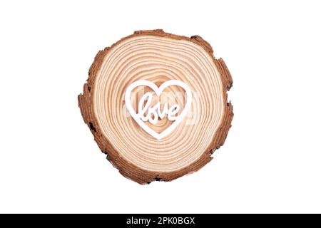 Baumstamm mit weißem Holzherz, das LIEBE auf weißem Hintergrund sagt Stockfoto