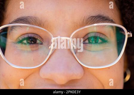 Nahaufnahme einer birassischen jungen Frau mit Brille und Blick in die Kamera Stockfoto