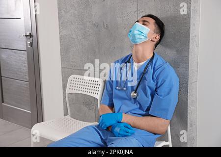 Erschöpfter Arzt schläft auf dem Stuhl im Flur des Krankenhauses Stockfoto