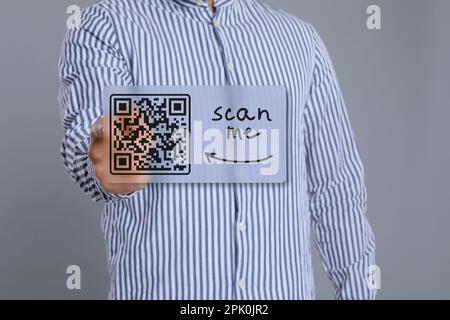 Mann zeigt auf Abbildung eines QR-Codes auf hellgrauem Hintergrund, Nahaufnahme Stockfoto