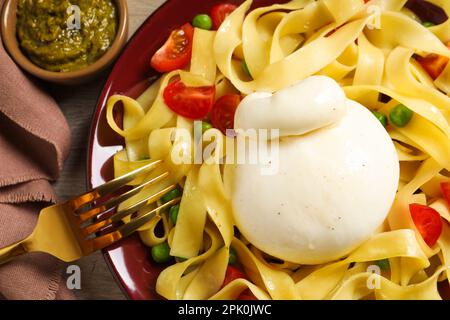 Teller mit köstlichen Pasta mit Burrata, Erbsen und Tomaten auf dem Tisch, Nahaufnahme Stockfoto