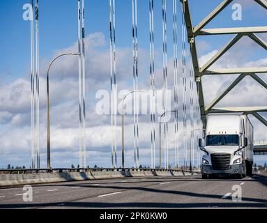 Hohes Fahrerhausprofil, weiß, langer Transporter, großer Sattelschlepper für den Transport von gewerblicher Fracht in einem Sattelanhänger für den Transport auf der Straße Stockfoto