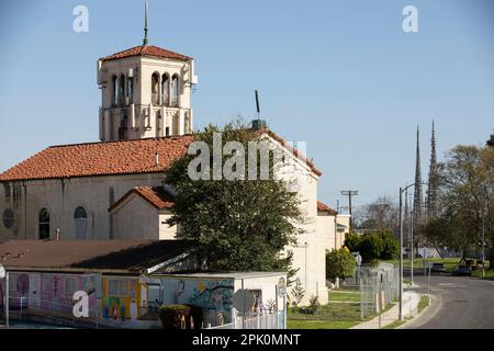 Watts, Kalifornien, USA - 25. Februar 2023: Die Nachmittagssonne scheint auf den berühmten Watts Towers und einer Kirche. Stockfoto