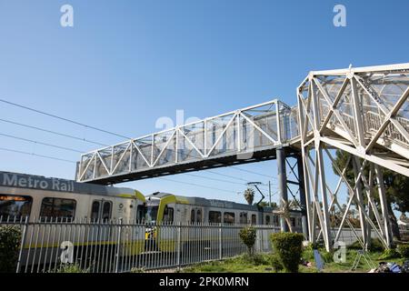 Watts, Kalifornien, USA - 25. Februar 2023: Eine U-Bahn-Linie Der Linie A (früher Blue) fährt unter einer Fußgängerbrücke durch. Stockfoto