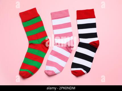 Gestreifte Socken auf hellrosa Hintergrund, flach liegend Stockfoto