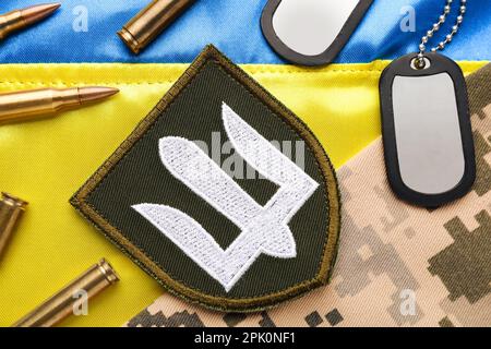 Ukrainischer Armeeschachtel in der Nähe von Tarngewebe, Kugeln und militärische ID-Tags auf der Nationalflagge der Ukraine, flach liegend Stockfoto