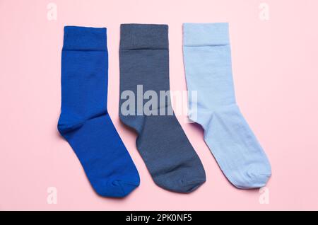 Verschiedene blaue Socken auf hellrosa Hintergrund, flach liegend Stockfoto