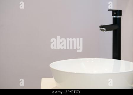 Wasserhahn- und Waschbecken-Design im Badezimmer mit leerer Wand. Selektiver Fokus des Bereichs. Offener Bereich zum Schreiben. Stockfoto