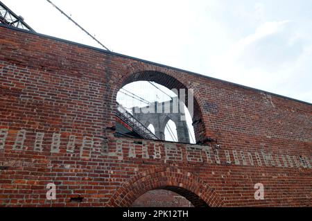 Die Brooklyn Bridge, gesehen durch ein Fenster des alten Tabak Warehouse in Fulton Landing State Park, New York City, USA Stockfoto