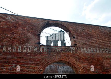 Die Brooklyn Bridge, gesehen durch ein Fenster des alten Tabak Warehouse in Fulton Landing State Park, New York City, USA Stockfoto