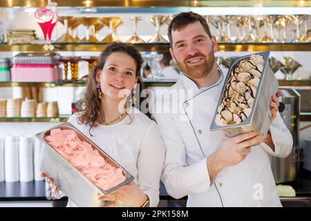 Schwabach, Deutschland. 23. März 2023. Der Eiscreme-Hersteller Luca de Rocco und seine Frau Francesca halten Behälter mit veganem Erdbeersorbet (l) und Marzipan-Eis in ihrem Eiscafé. Noch bevor die Eissaison wirklich losgeht, ist eines sicher: Veganes Eis wird weiterhin trendig sein. Aber auf welche neuen Geschmacksrichtungen können sich Eiscreme-Fans dieses Jahr freuen? (Zu dpa: "Fruit Prosecco oder klassische Vanille? The Ice Cream Trends 2023') Kredit: Daniel Karmann/dpa/Alamy Live News Stockfoto