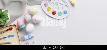 Ansicht des Arbeitsplatzes von oben mit schönen und farbenfrohen Ostereiern, Palette, Malpinseln, Acrylfarben und Kopierbereich auf weißem Hintergrund. Osterholid Stockfoto