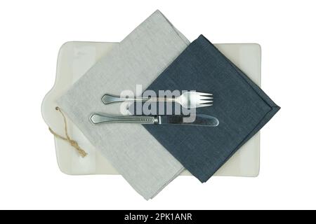 Küchenbrett mit beigefarbenem Textilhandtuch und einer Gabel mit Messer isoliert auf weißem Hintergrund. Draufsicht. Stockfoto