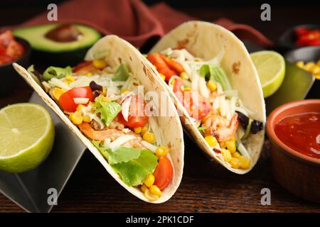 Köstliche Tacos mit Garnelen, Käse und Limette auf einem Holztisch, Nahaufnahme Stockfoto