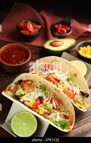 Köstliche Tacos mit Garnelen, Käse und Limette auf einem Holztisch Stockfoto