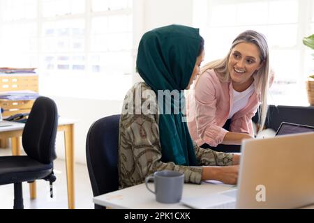 Vielbeschäftigte, vielseitige Geschäftsfrauen, die über die Arbeit diskutieren und Tablets in modernen Büros verwenden Stockfoto