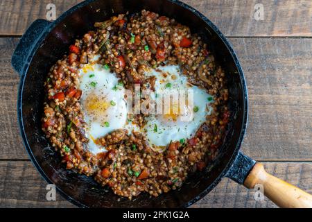 Gekochter Buchweizen mit Spiegeleiern, Paprika, Karotten und Zwiebeln, Nahaufnahme, Ukraine. Hintergrund für das Essen. Gesunde Ernährung Stockfoto