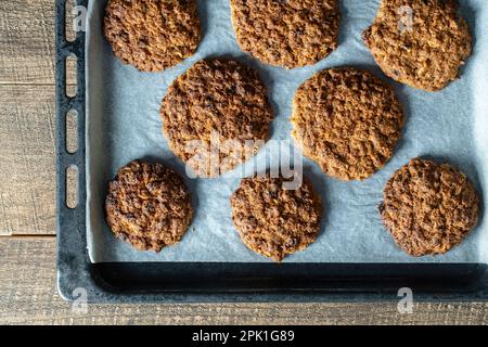 Köstliche Haferbrei-Kekse mit Walnüssen auf Backpapier, Nahaufnahme, Draufsicht Stockfoto