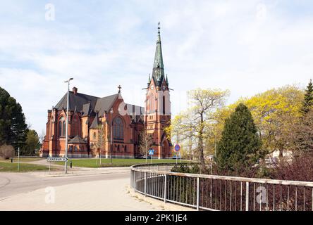 UMEA, SCHWEDEN, AM 25. MAI 2012. Blick auf die 1894 in Ziegelsteinen erbaute Stadtkirche. Straße, Schild und Sonnenschein. Editorial use. Stockfoto