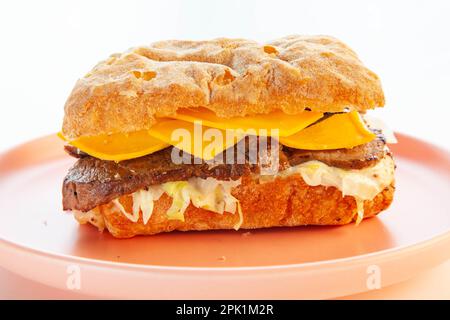 Philly Cheese Steak Ciabatta Sandwich serviert auf einem rosa Teller. Stockfoto