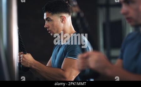 Auf dem richtigen Weg, um stark zu werden. Ein sportlicher junger Mann, der im Fitnessstudio trainiert. Stockfoto