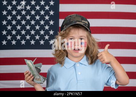 Amerikanische Träume. Ein Junge mit hundert Dollar Geld, isoliert im Studiohintergrund. Kind mit amerikanischer Flagge, Unabhängigkeitstag 4. juli. Vereinigte Staaten Stockfoto