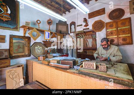 Einer der Handwerker, die in einem Geschäft in der Anlage arbeiten. Er ist Holzschnitzer, Kisten, andere Sachen. Im Emirates Heritage Club Heritage Village in Abu DH Stockfoto