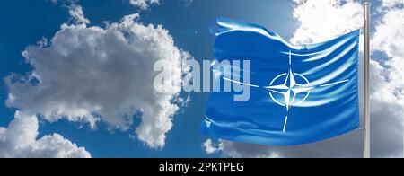 Die Flagge der NATO winkt im Wind auf einem Fahnenmast gegen den Himmel Stockfoto