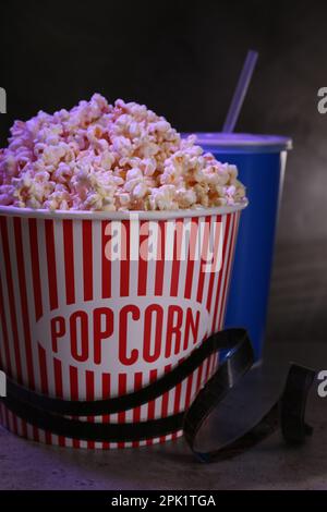 Köstliches Popcorn, Getränk und Klebeband auf grauem Tisch Stockfoto