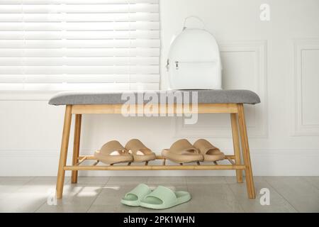 Elegante Gummischuhe und Aufbewahrungsbank mit Schuhen im Zimmer Stockfoto