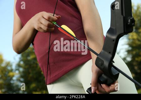 Eine Frau mit Pfeil und Bogen, die im Freien Bogenschießen praktiziert, Nahaufnahme Stockfoto