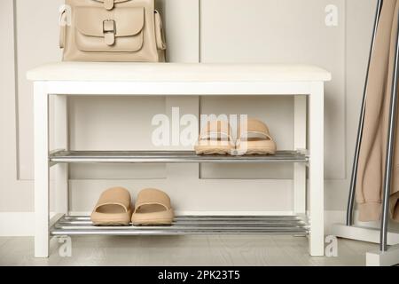 Aufbewahrungsbank mit Paar Gummipantoffeln in der Nähe der weißen Wand im Zimmer Stockfoto