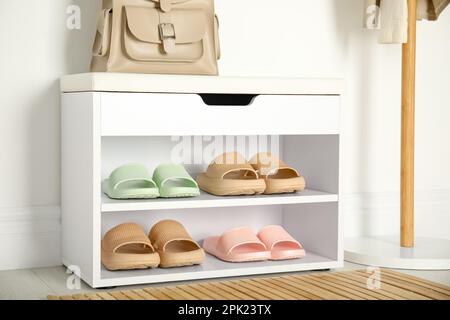 Aufbewahrungsschrank mit verschiedenen Paar Gummipantoffeln in der Nähe der weißen Wand im Raum Stockfoto