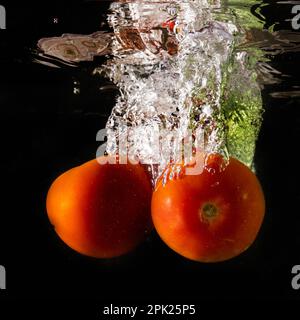 Reife Tomate fällt tief unter Wasser mit einem big Splash. Stockfoto