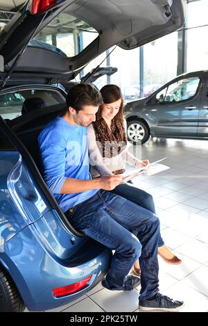 Junges Paar im Showroom des Autohauses kaufen und Prüfung der Fahrzeuge Stockfoto