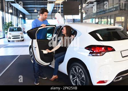 Junges Paar im Showroom des Autohauses kaufen und Prüfung der Fahrzeuge Stockfoto