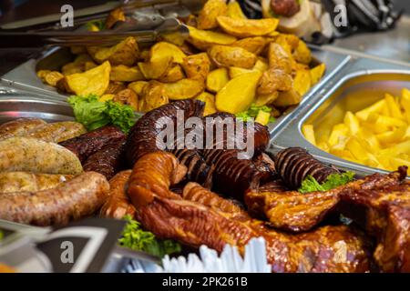 Gegrillte Würstchen, Gemüse, Salate auf der Theke im Food Court. Straßenküche. Stockfoto