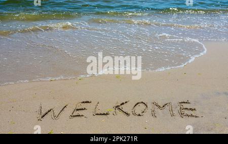 Handschreiber-Inschrift Welkome-Wort über tropischen Sandstrand, Reise-Konzeptkarte für Urlaub. Stockfoto