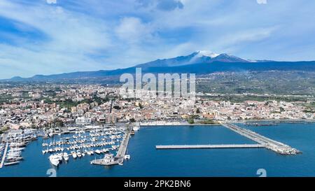 Riposto Sommerziel - Luftaufnahme vom Seehafen mit Booten an sonnigen Tagen mit Ätna-Vulkan im Hintergrund mit Meer Stockfoto