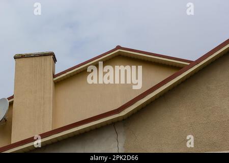 Metalldach eines Einzelhauses und Schornstein am Himmel, Dachziegel aus Metall, Dachrinnen. Stockfoto