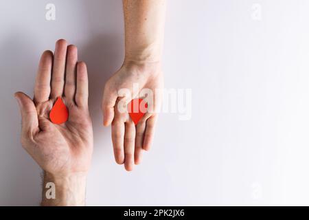 Hände einer weißen Frau und eines Mannes mit Bluttropfen auf weißem Hintergrund mit Kopierraum Stockfoto