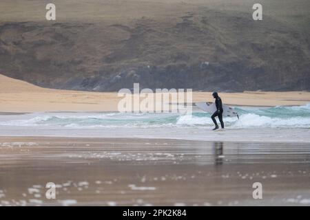 Isle of Lewis, Schottland. 5. April 2023 Wetter in Großbritannien: Ein nasser und windiger Start in die Osterferien auf der Isle of Lewis. Ein einsamer Surfer trotzt den Wellen am Eoropie Beach. Kredit: Bradley Taylor / Alamy Live News Stockfoto