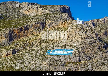 Weiße Kapelle und gemalte griechische Flagge auf dem Hügel über Pothia, der wichtigsten Stadt von Kalymnos, griechische Insel, Dodekanesische Inseln, Griechenland Stockfoto