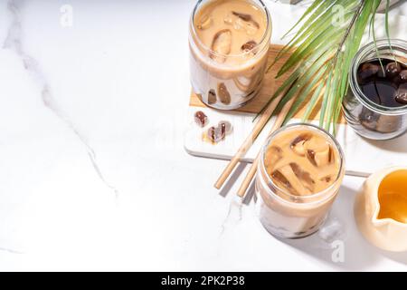 Iced Tapica Coffee Latte oder boba Pearl Bubbles Milchtee, asiatisches trendiges kaltes Kaffeegetränk mit Tapiokasseln und zerstoßenem Eis, auf weißem Marmorhintergrund Stockfoto