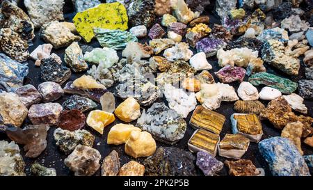 Mehrfarbige Raue Edelsteine, Draufsicht. Große Sammlung vieler heilender Kristalle in einem Edelsteinladen. Vibrant Shiny Tiger Eye, Amethyst, Citrine, Smoky Quartz, Fuchsite, Weiße Quarzsteine zum Verkauf. Stockfoto